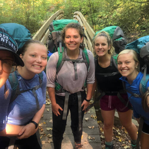 5 backpackers posing for a picture in front of a wooden bridge at the Manistee River Trail